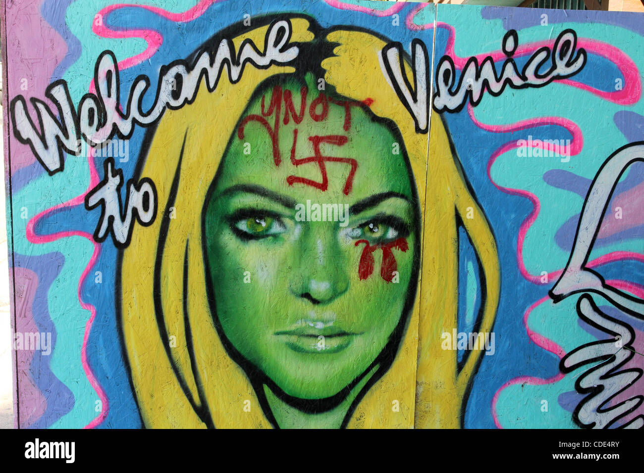 Feb. 3, 2011 - Venice, California, U.S - A man walks past Venice artist Jules MuckÃ”s Ã’Welcome to VeniceÃ“ painting of Lindsay Lohan that was defaced with a swastika on her forehead and blood red tears from her eye. Many residents of Venice Beach are unhappy that the troubled actress has recently m Stock Photo