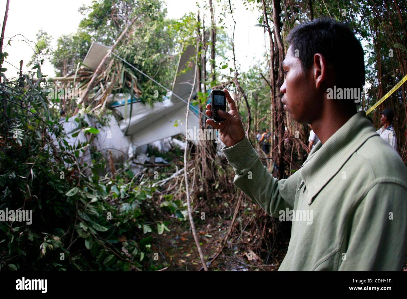 Feb 12, 2011 - Bintan, Riau, Indonesia - A man taking photos of the plane. Officials say an Indonesian light transport plane has crashed on Bintan island after undergoing engine maintenance, killing all five people on board. A Transportation Ministry spokesman, Bambang Ervan, says the Cassa 212 turb Stock Photo