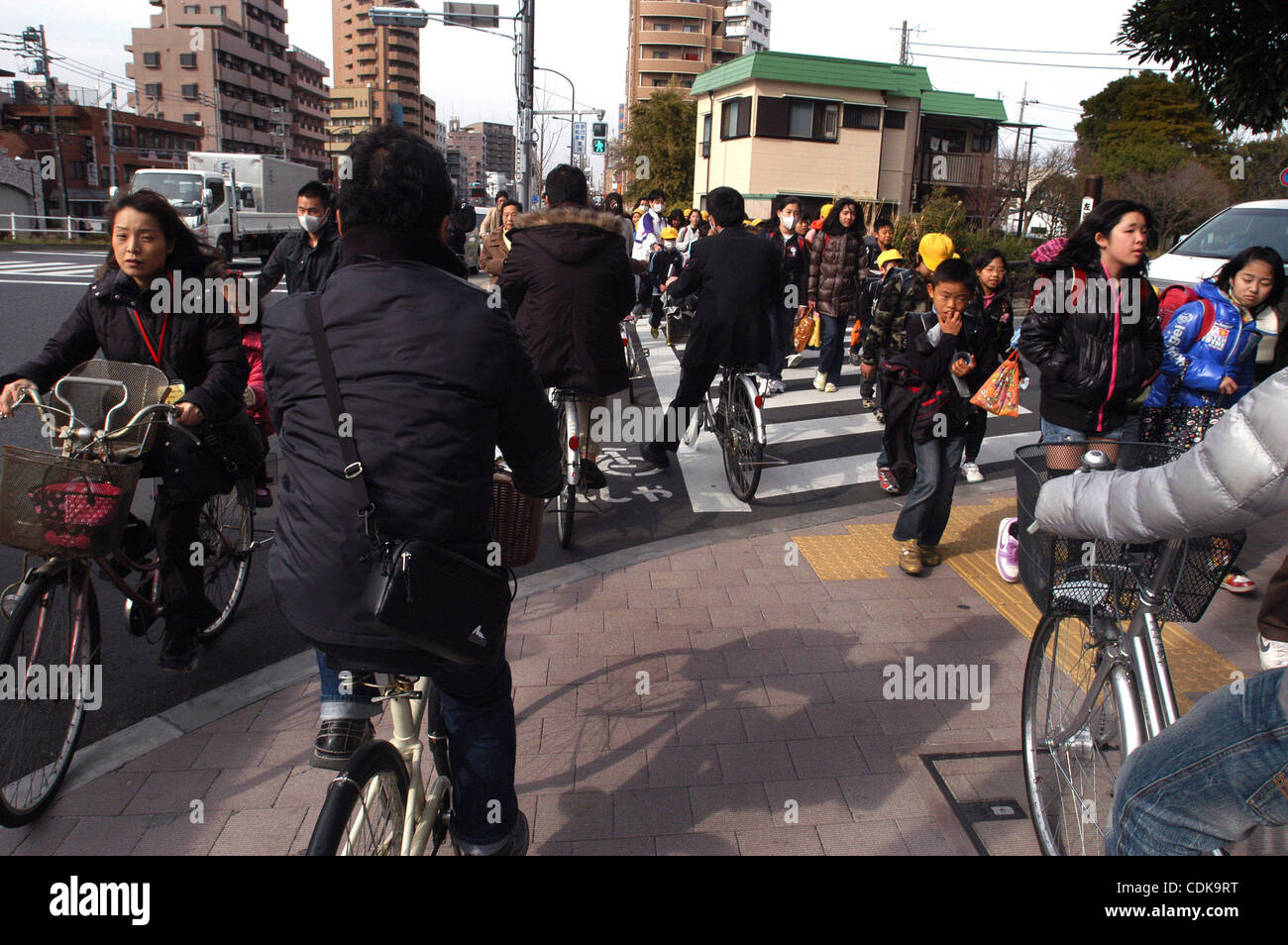 Mar 14, 2011 - Edogawa-Ku, Tokyo, Japan - People ride their bicycles on a busy street in Tokyo as elementary students pass by, days after Japan's 9.0 earthquake and tsunami. A massive, powerful and deadly 9.0 magnitude earthquake, the world's fifth largest quake ever recorded, struck at 2:46 p.m. lo Stock Photo