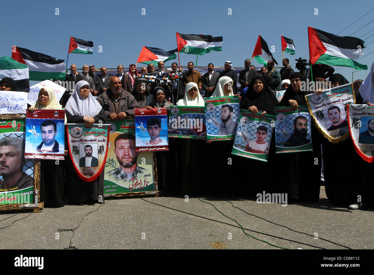 Palestinians wave their national flag and hold pictures of Palestinian prisoners jailed in Israel during a sit-in in Beit Hanun, northern Gaza Strip, on March 30, 2011 as hundreds of people across Israel and Palestinian territories were holding a series of rallies marking 'Land Day,' recalling an in Stock Photo