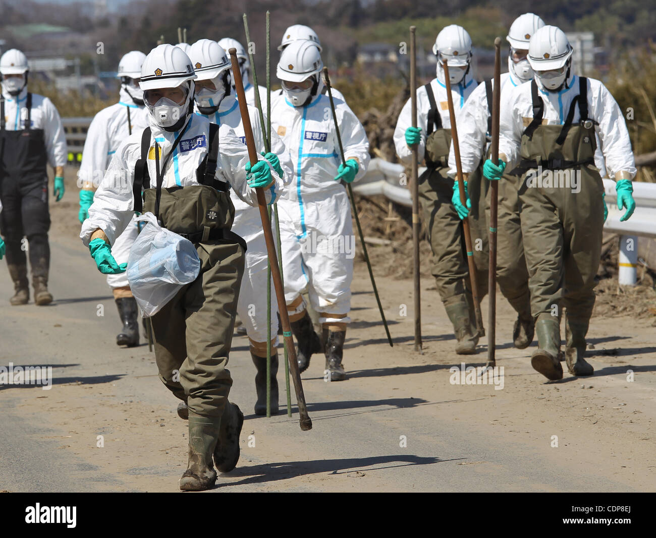 Apr. 17, 2011 - Namie, Japan - Police officers wearing the radiation protective gears search for missing persons in where the Fukushima Daiichi nuclear plant in Namie Town, Fukushima Prefecture, Japan. The Japanese Government has set up a policy to appoint certain area within the distance of 20 km f Stock Photo