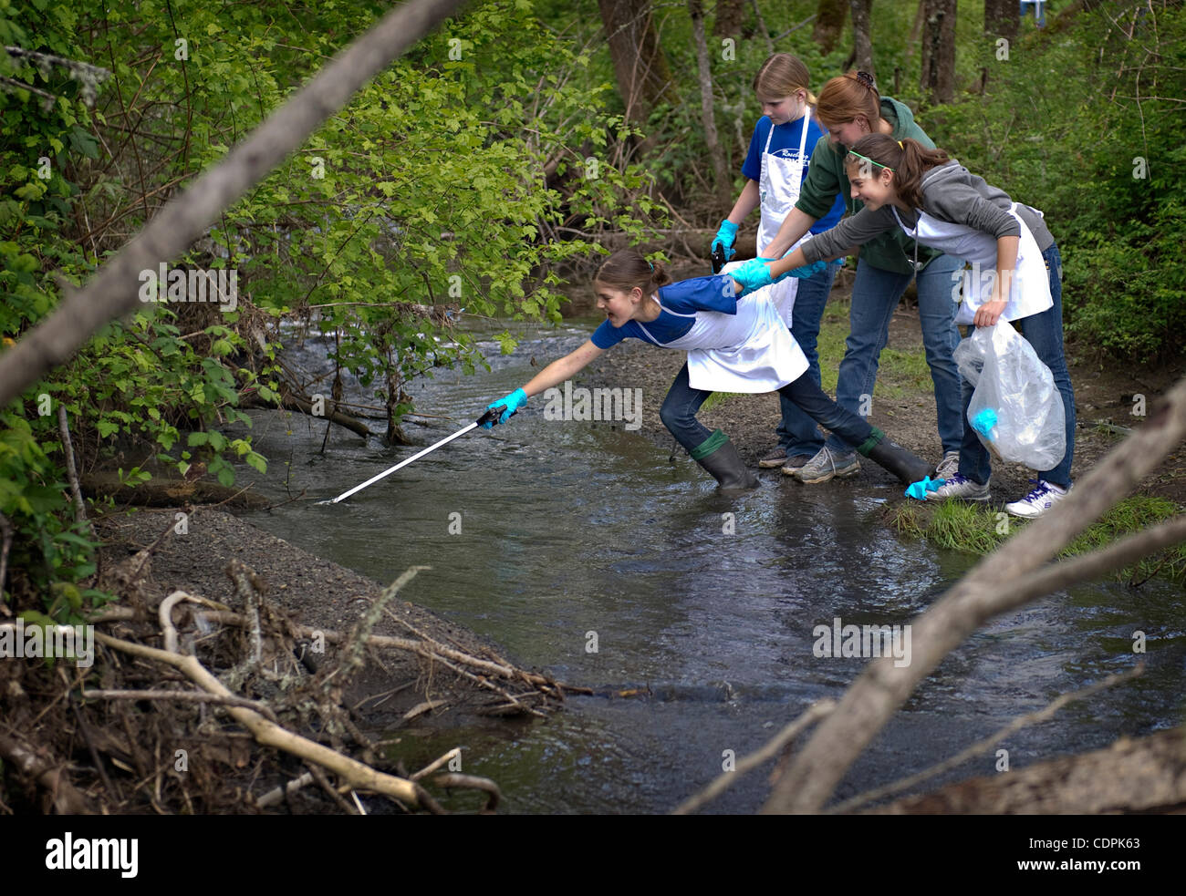 Apr. 27, 2011 - Roseburg, Oregon, U.S - JALEN ROBLES, 10, left, gets help from her sister KELSEY  ROBLES , 12, friend ALEXA LIGON , 10, and her mother HEIDI ROBLES while reaching for a piece of trash in a creek during a community cleanup day at a Charles Gardiner Park in Roseburg. The park is the si Stock Photo