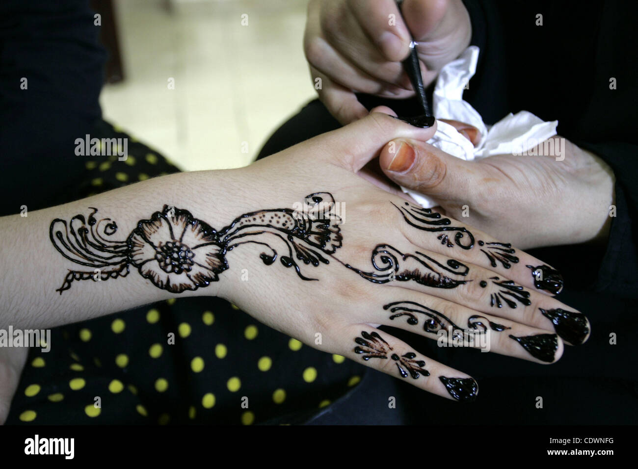 A Palestinian woman applies henna on the hand of a girl during a summer ...