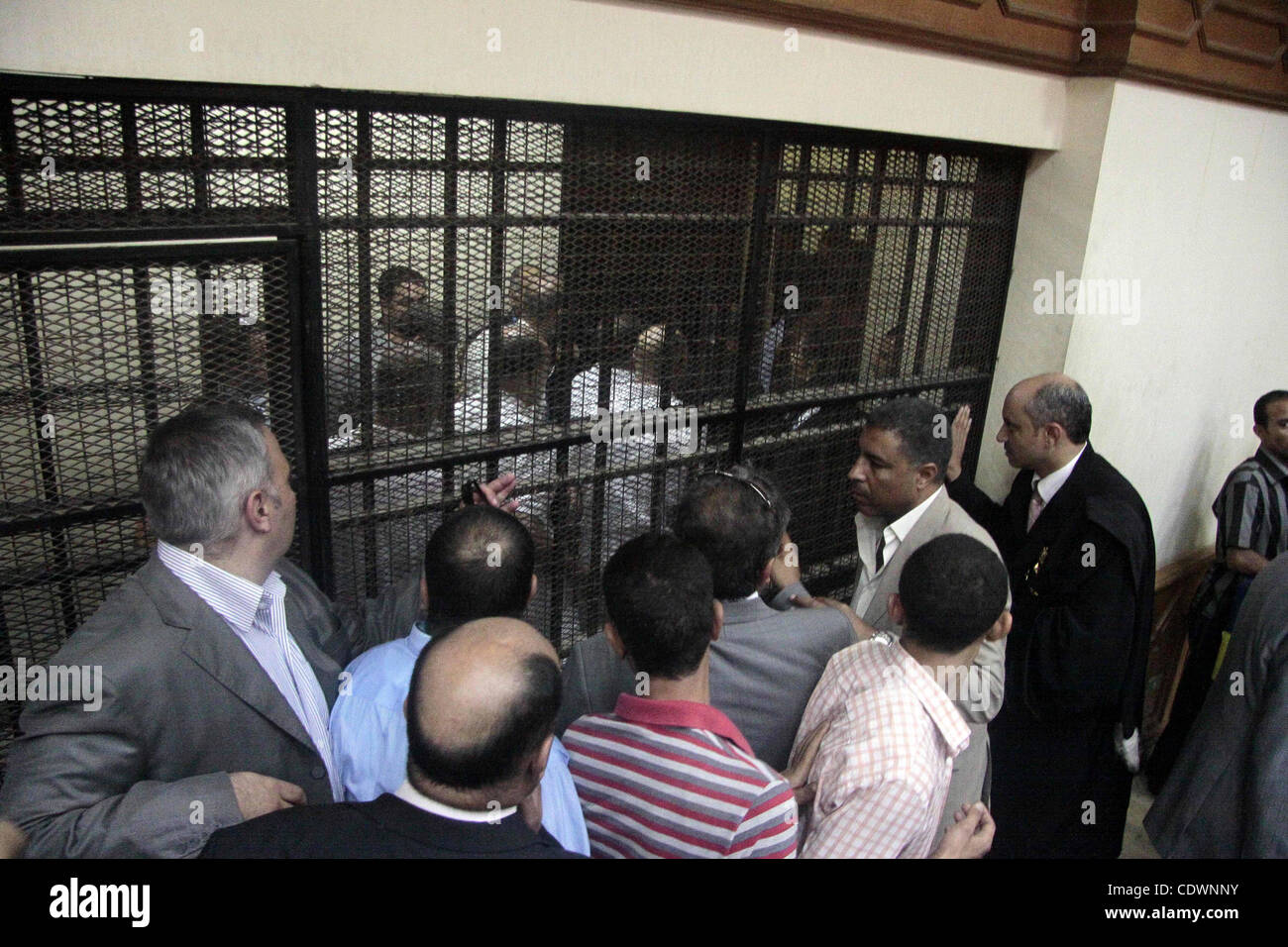 Journalists and bodyguards stand in the Cairo court room as defendants ...