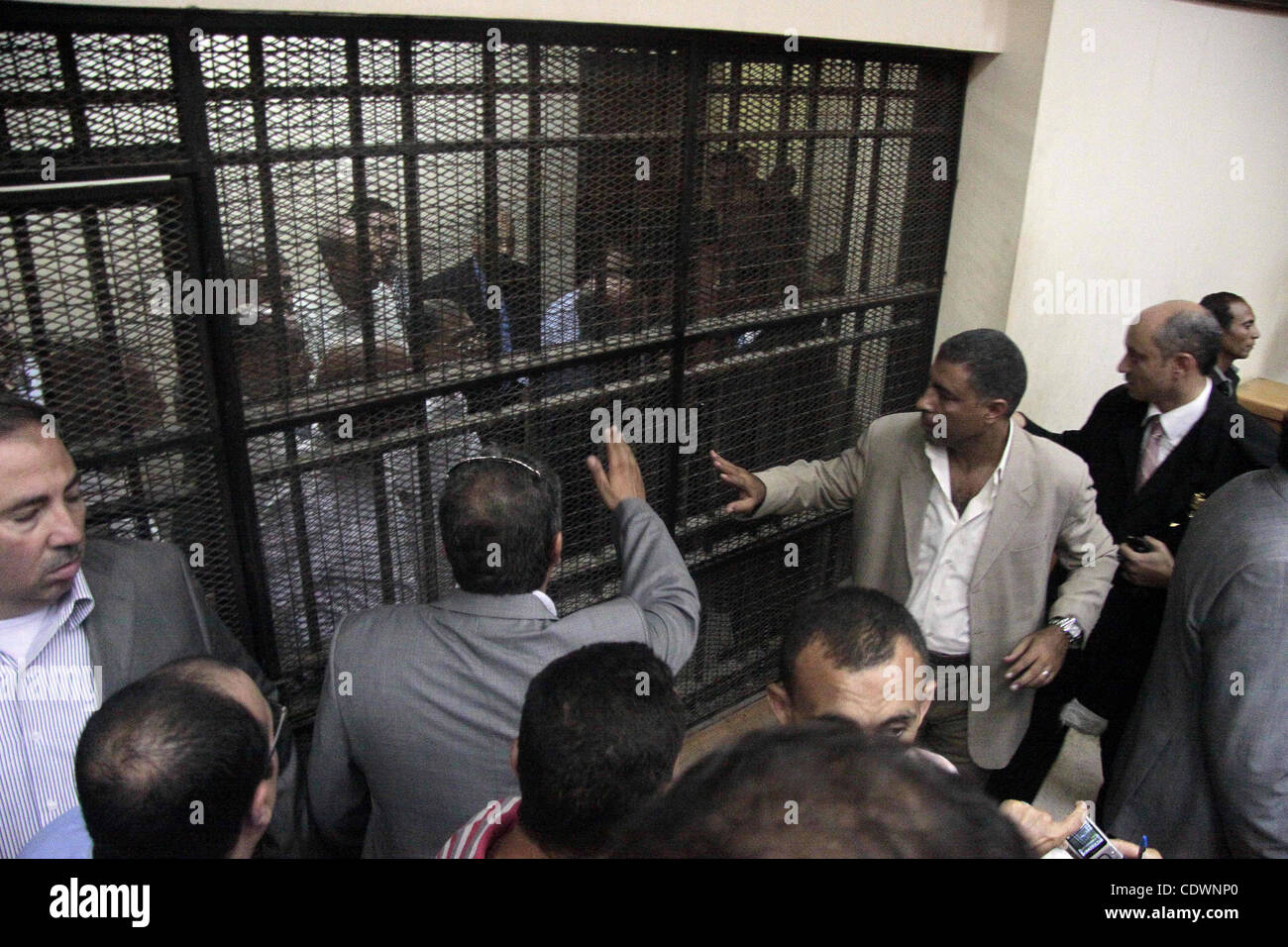 Journalists and bodyguards stand in the Cairo court room as defendants ...