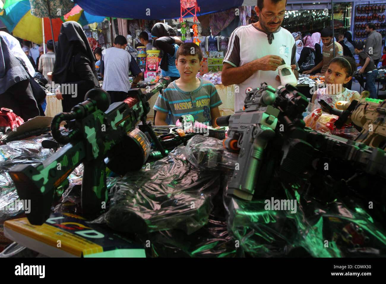 Aug. 29, 2011 - Gaza City, Gaza Strip - Palestinian vendors display toy machine guns and goods for sale during preparations for Eid al-Fitr at the main market, in Gaza city. Muslims throughout the world buy clothes, sweets and other popular items to prepare for The Eid aL-Fitr ,the festivities marki Stock Photo