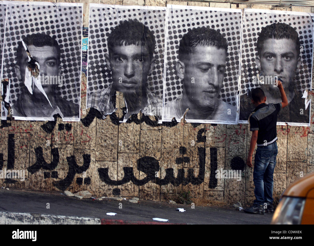 Sept. 6, 2011 - Ramallah, West Bank - A Palestinian man defaces large black and white photographs taken by French street artist JR. JR's project entails having Palestinian and Israeli portraits taken which are then printed and pasted onto walls In Israel and the West Bank, as a way of making the two Stock Photo