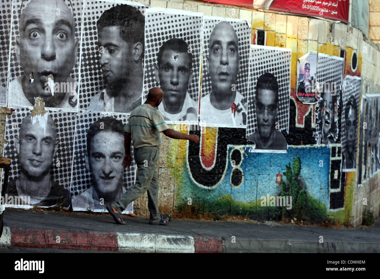 A Palestinian man walks past large black and white photographs taken by French street artist JR of Palestinians, on September 6, 2011, in the West Bank city of Ramallah. JR's project entails having Palestinian and Israeli portraits taken which are then printed and pasted onto walls In Israel and the Stock Photo