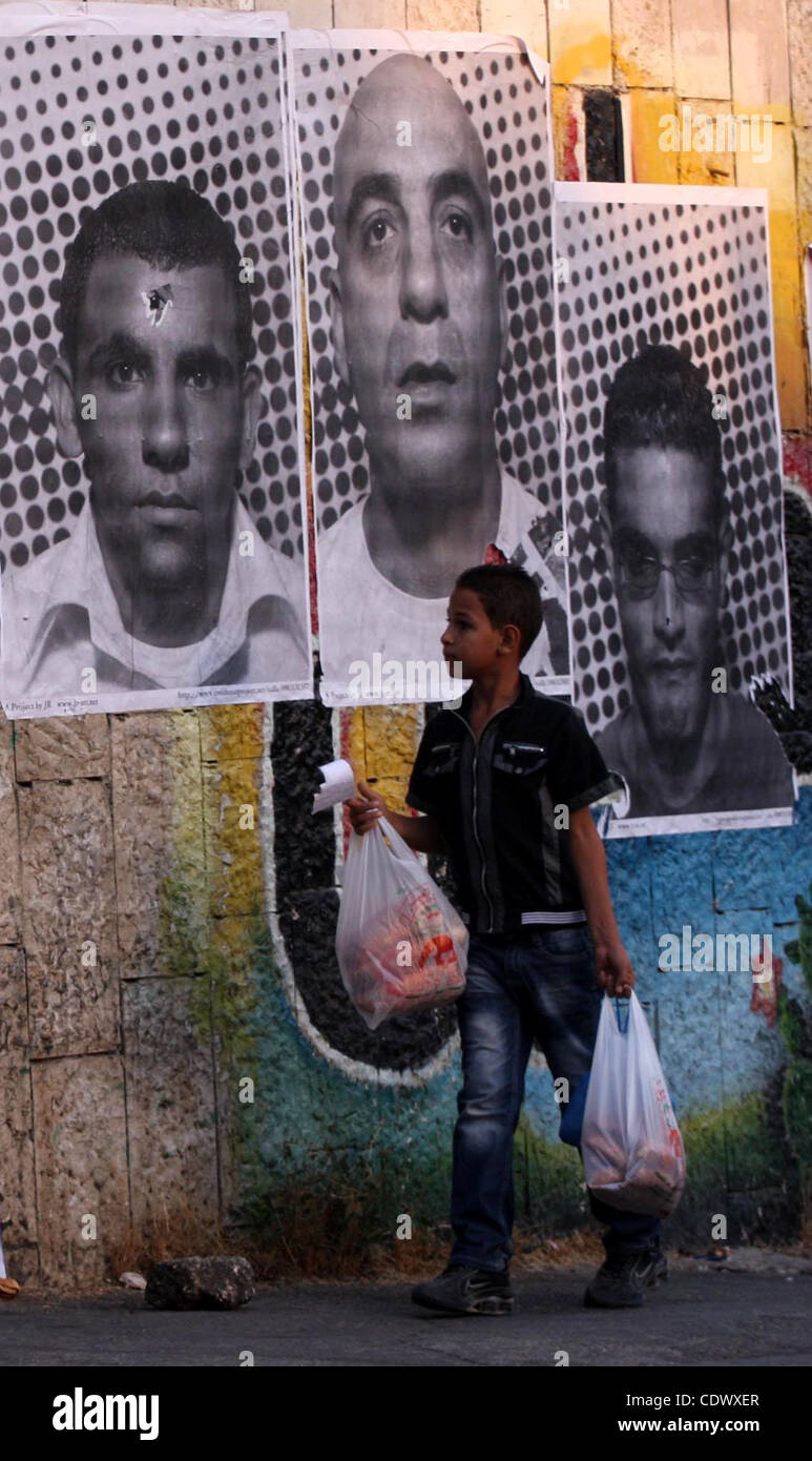 A Palestinian boy walks past large black and white photographs taken by French street artist JR of Palestinians, on September 6, 2011, in the West Bank city of Ramallah. JR's project entails having Palestinian and Israeli portraits taken which are then printed and pasted onto walls In Israel and the Stock Photo