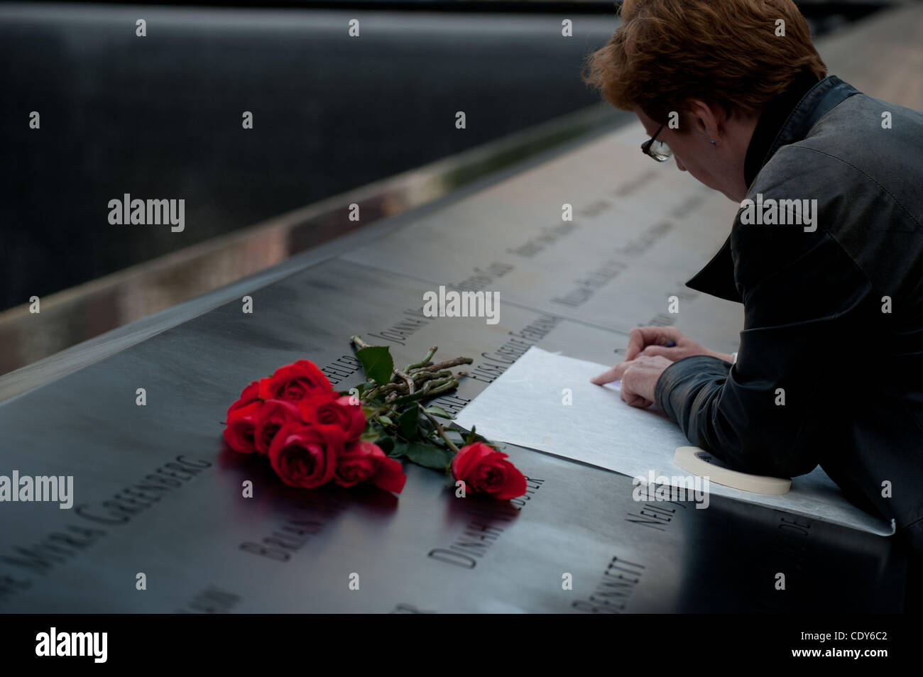 Sep. 11, 2011 - New York, New York, U.S. - A woman lays roses and makes paper tracing of a loved ones name on the memorial. Many people came to pay their respects during a memorial service to commemorate the Tenth Anniversary of the attack of the World Trade Center on September 11 2001. (Credit Imag Stock Photo