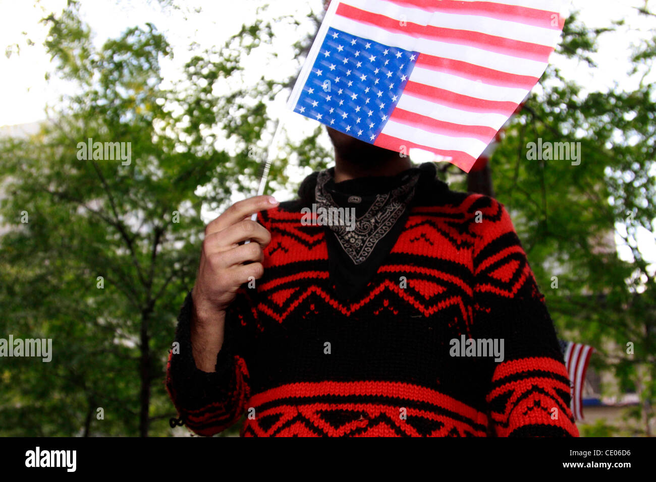 A protester called KV displays an upside down American flag at Occupy Wall Street. Some call it a shanty town and a circus. Others call it a political and social revolution. Stock Photo