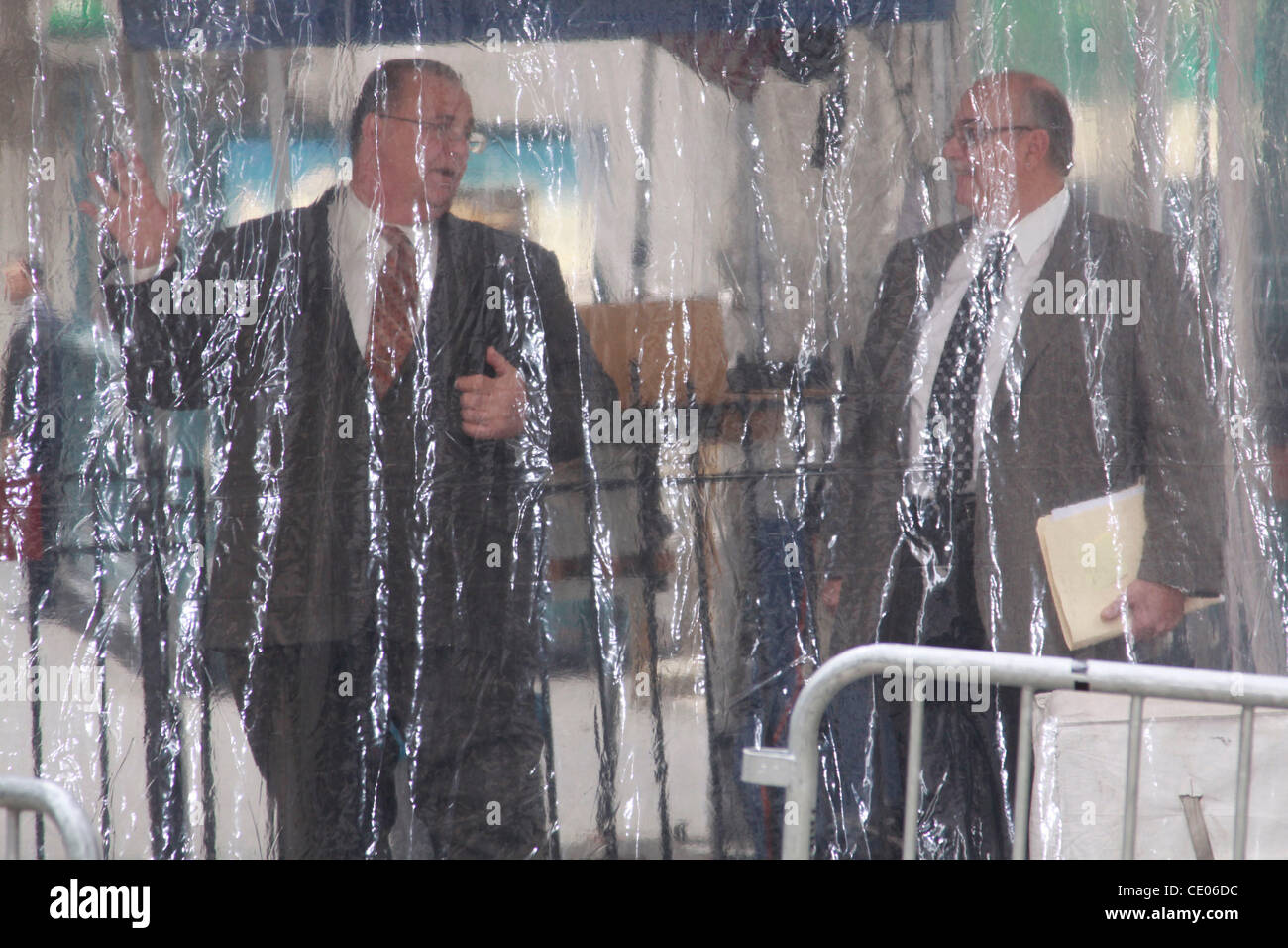 Two men behind a plastic curtain on Wall Street. Stock Photo