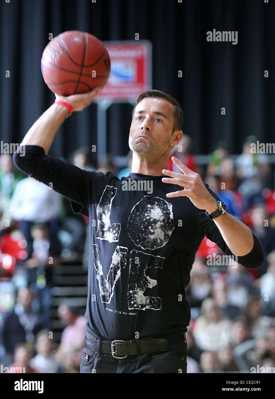 Kai Pflaume throwing a ball during the intermission of a basketball match  between FC Bayern and ETB Essen at Olymiahalle hall. The German TV host  missed the hoop and the chance to