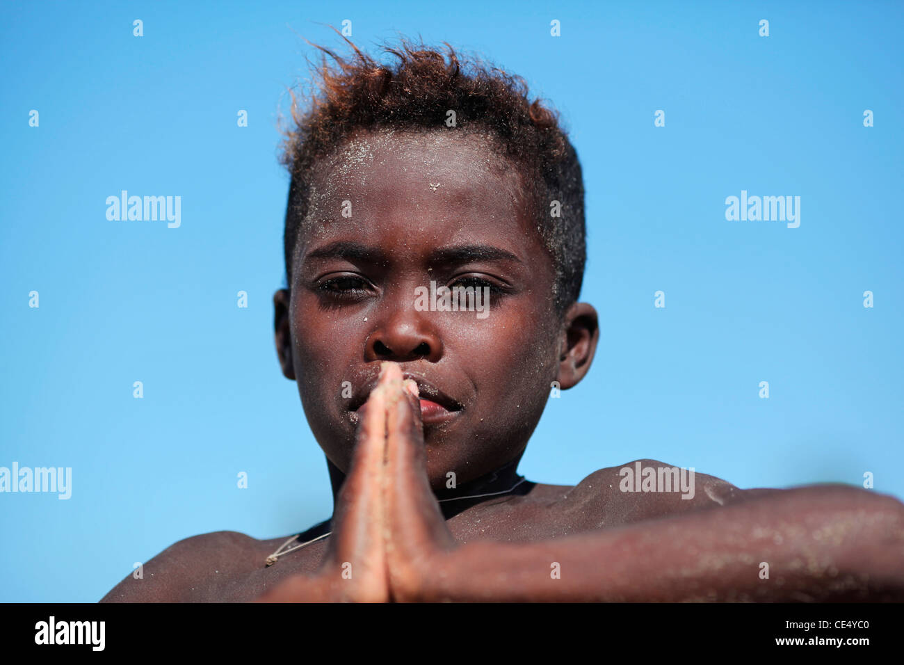 Portrait of a malagasy boy of the Vezo ethnic group in a praying or martial arts stance, near Morondava, Madagascar. Stock Photo
