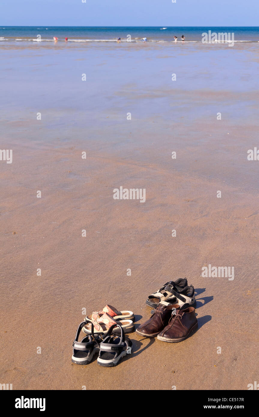 Four  pairs of shoes on huge desert  sand beach . Stock Photo