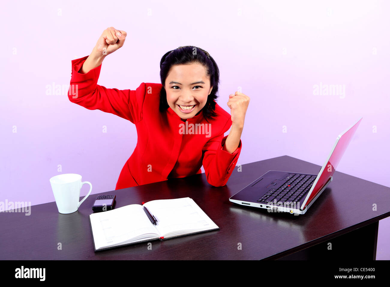 woman at office using a laptop and raised she hands Stock Photo