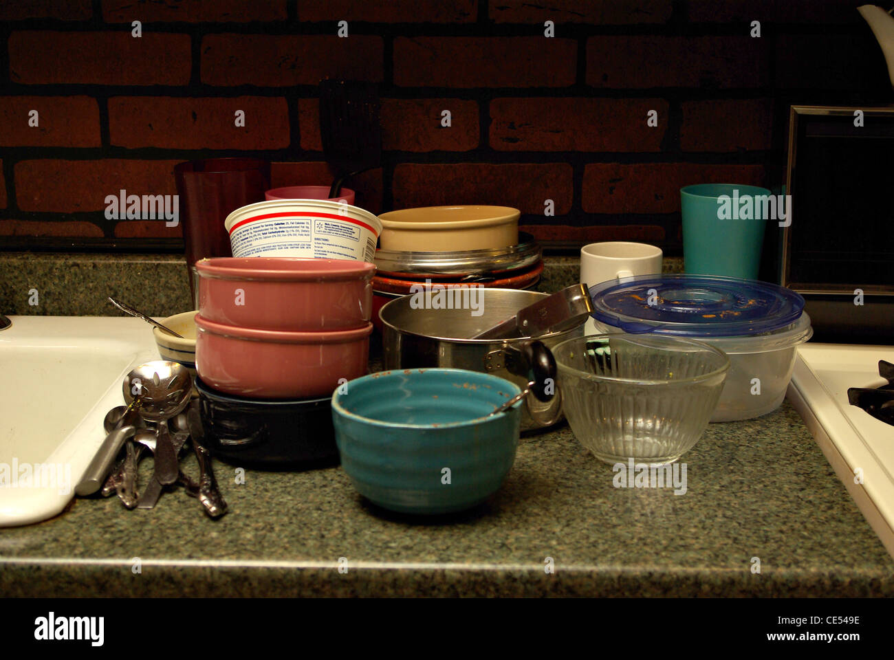 A pile of dirty dishes sits on the counter top waiting to be washed Stock Photo