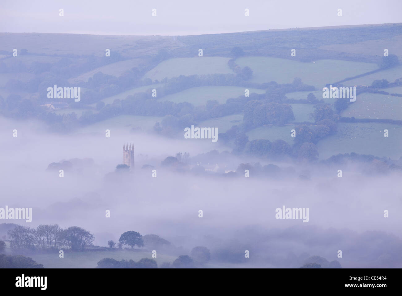 Morning mist swirls around the church tower of Widecombe in the Moor, Dartmoor, Devon, England. Autumn (September) 2011. Stock Photo