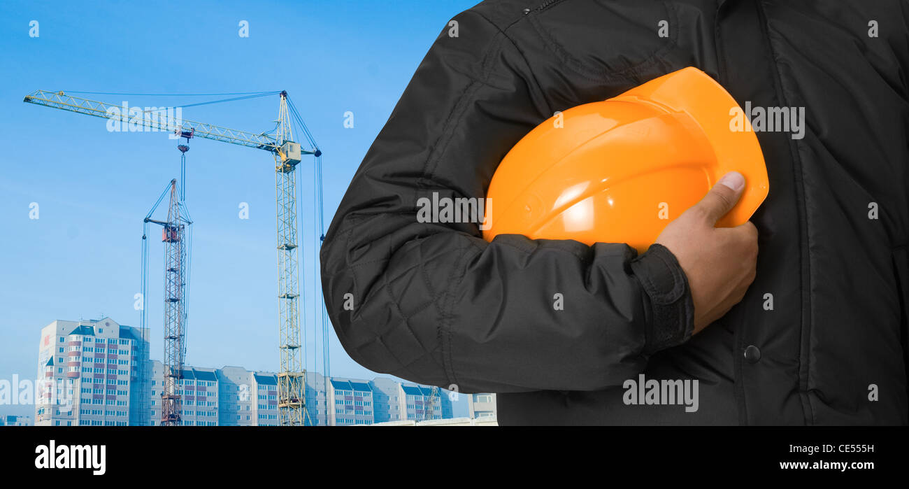 Closeup of builder with helmet on building panorama background Stock Photo