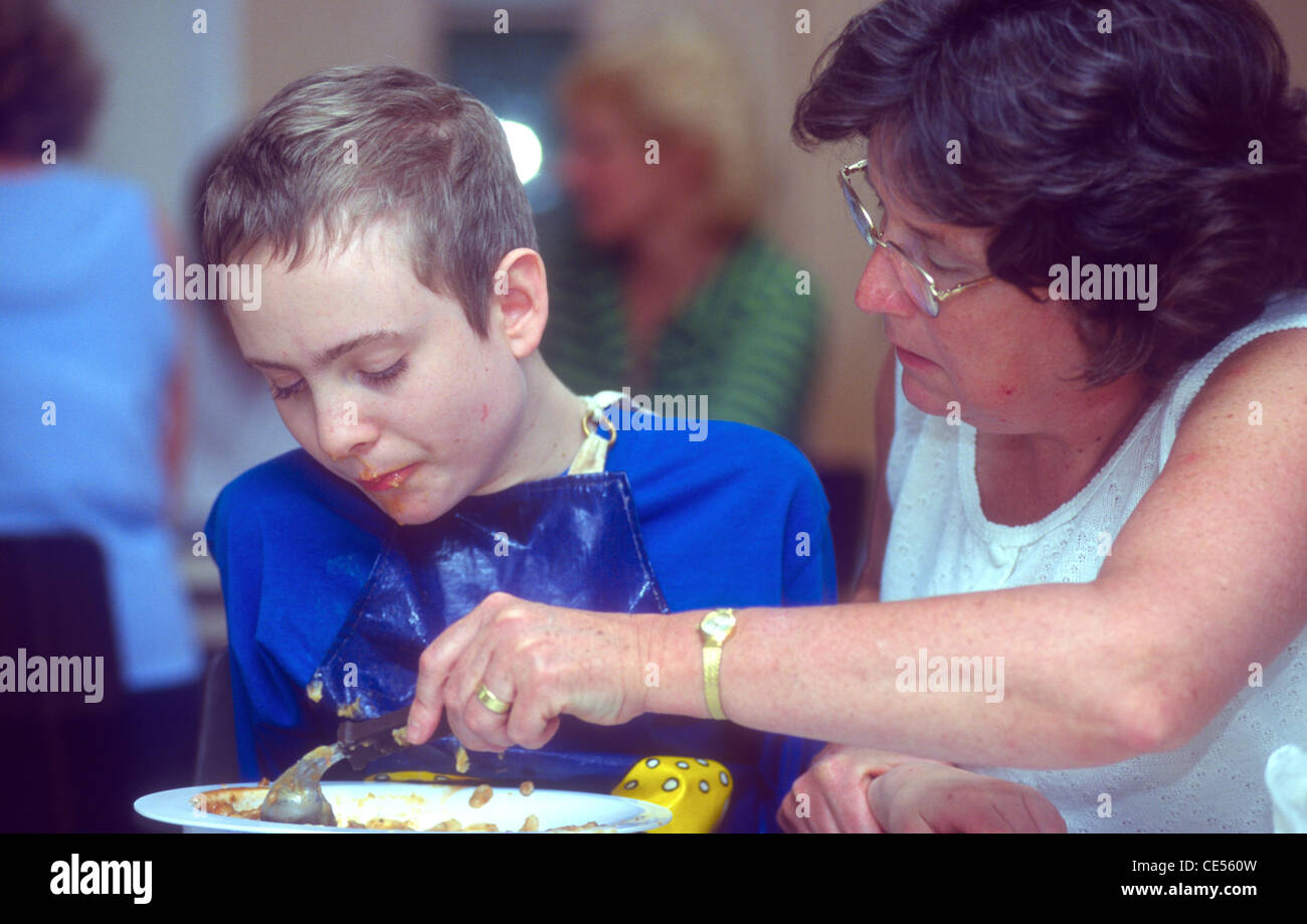 Autistic pupil receiving assistance at lunchtime, Moorcroft Special School, Uxbridge, Middlesex, UK. Stock Photo