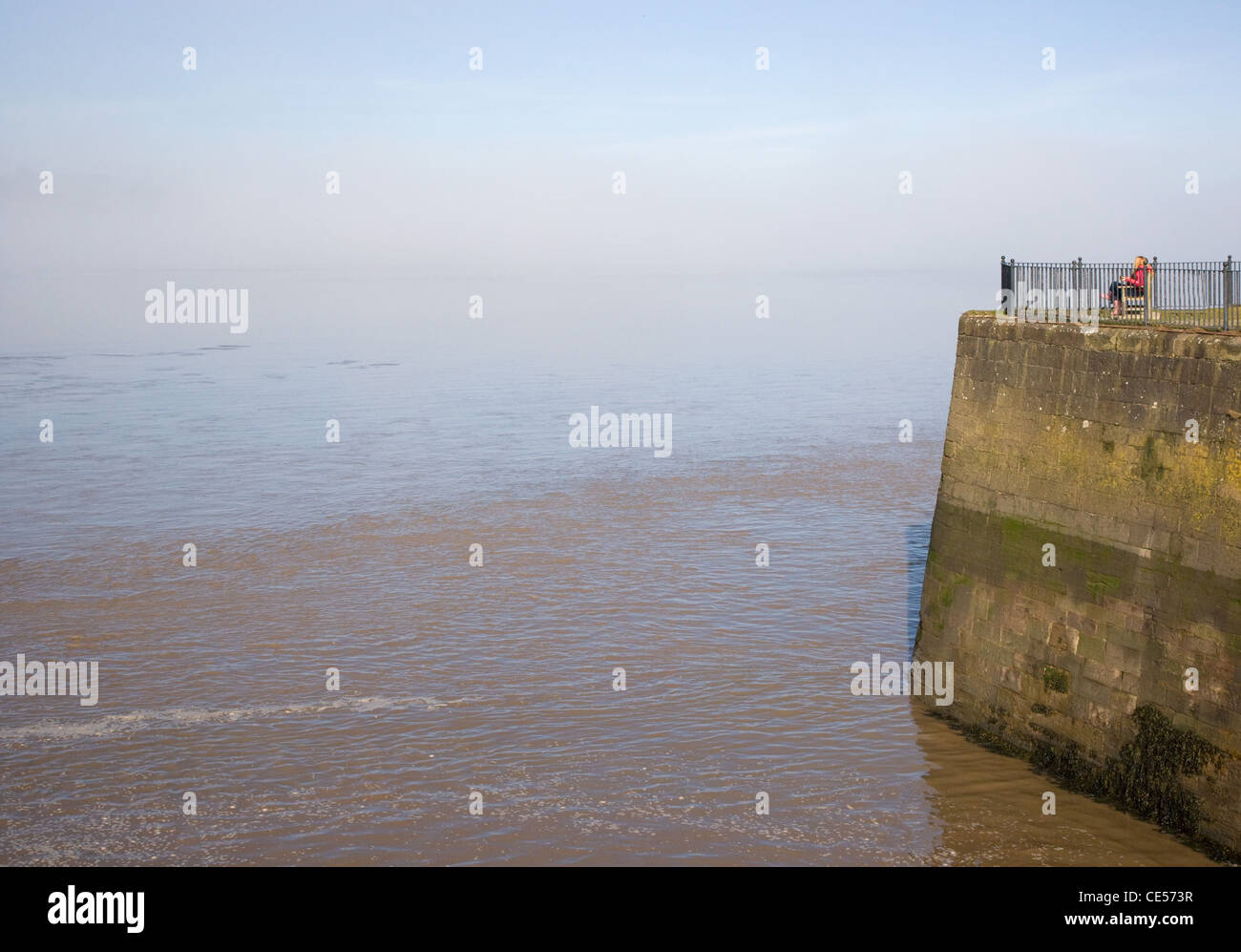 A woman looks out over a foggy Severn estuary at Sharpness in Gloucestershire UK Stock Photo