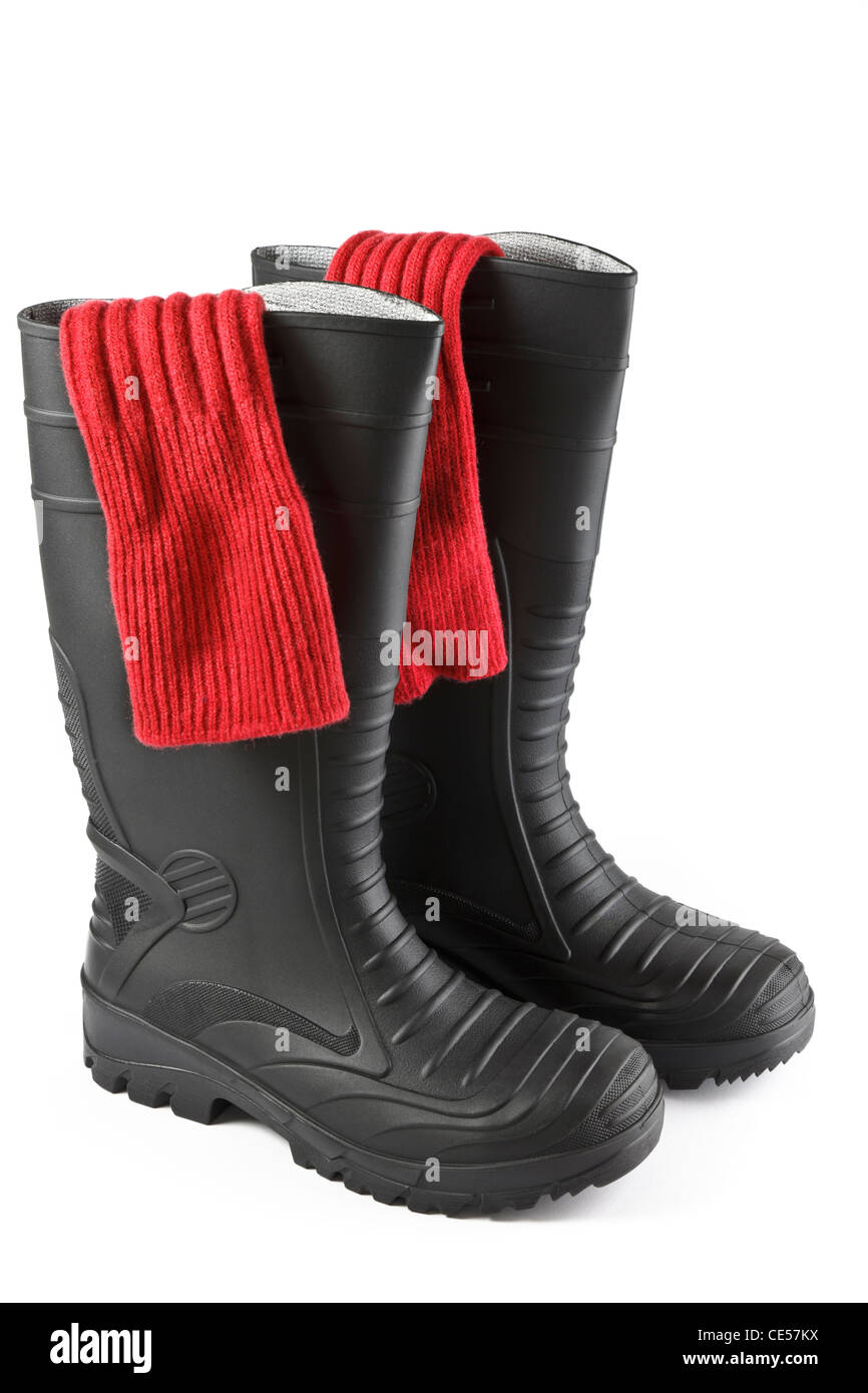 One pair of red socks inside a pair of black rubber safety wellington boots isolated on a white background. UK Stock Photo