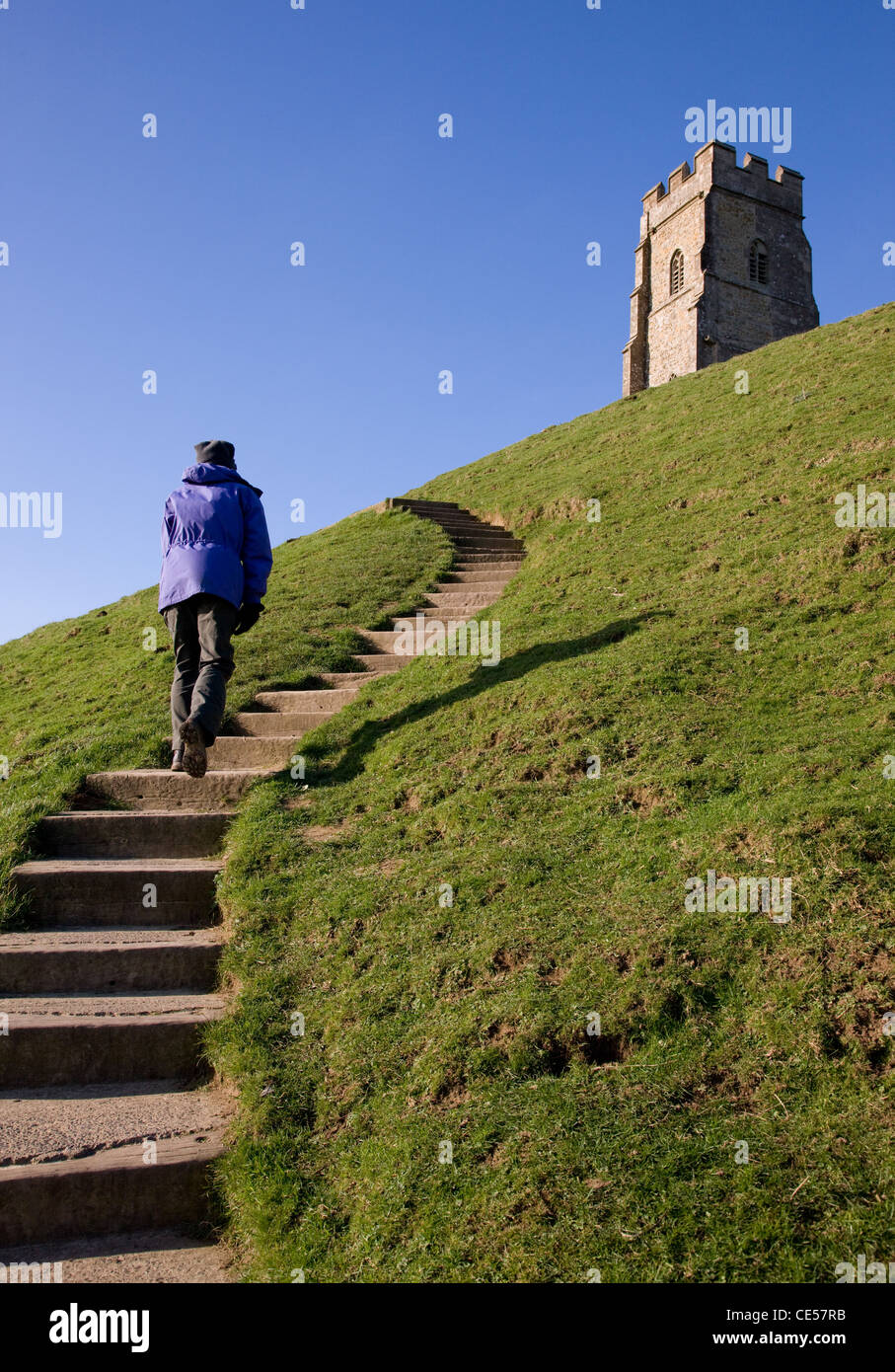 A woman climbs up the steep steps to St Michael's Tower on Glastonbury Tor in Somerset UK Stock Photo