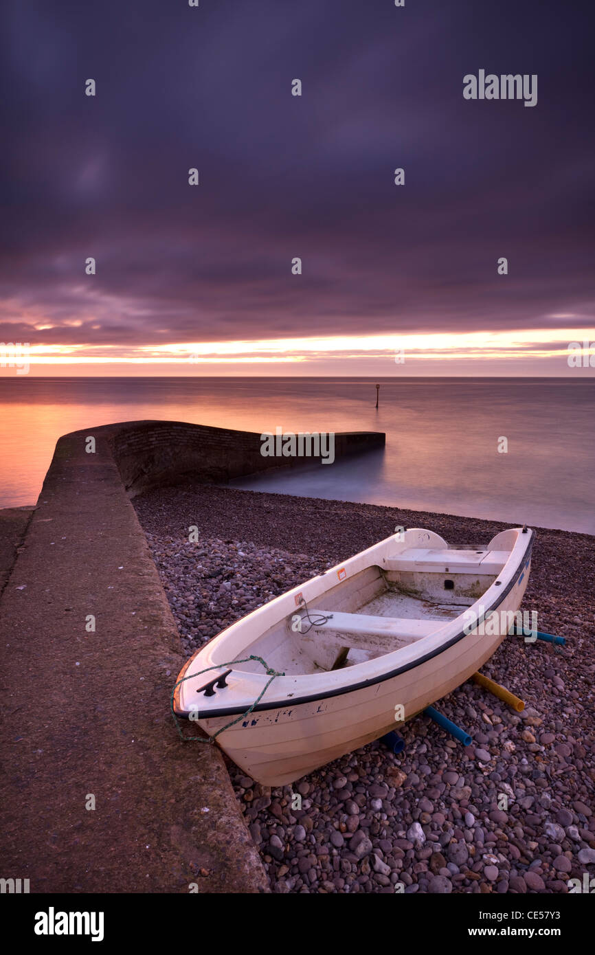 Fishing boat on Sidmouth beach at dawn, Sidmouth, Devon, England. Winter (January) 2012. Stock Photo