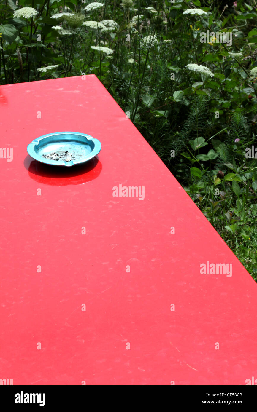 Close-up of ash tray on a red iron garden table standing on a garden meadow Stock Photo