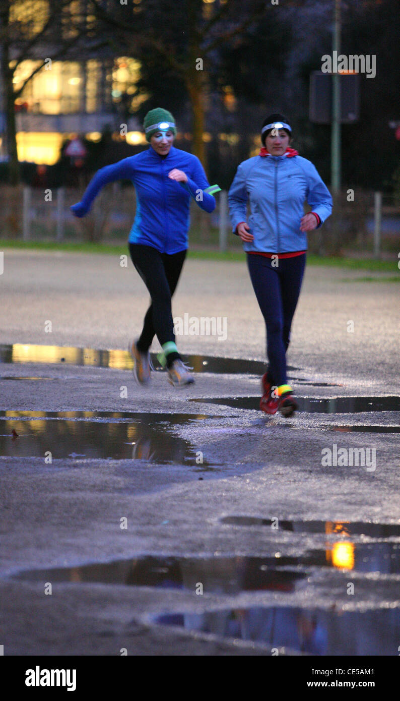 Two young women jogging at night in winter, fall. With headlamps in the