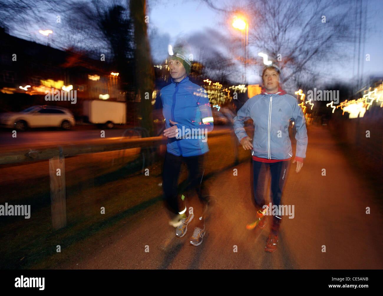 Two young women jogging at night in winter, fall. With headlamps in the