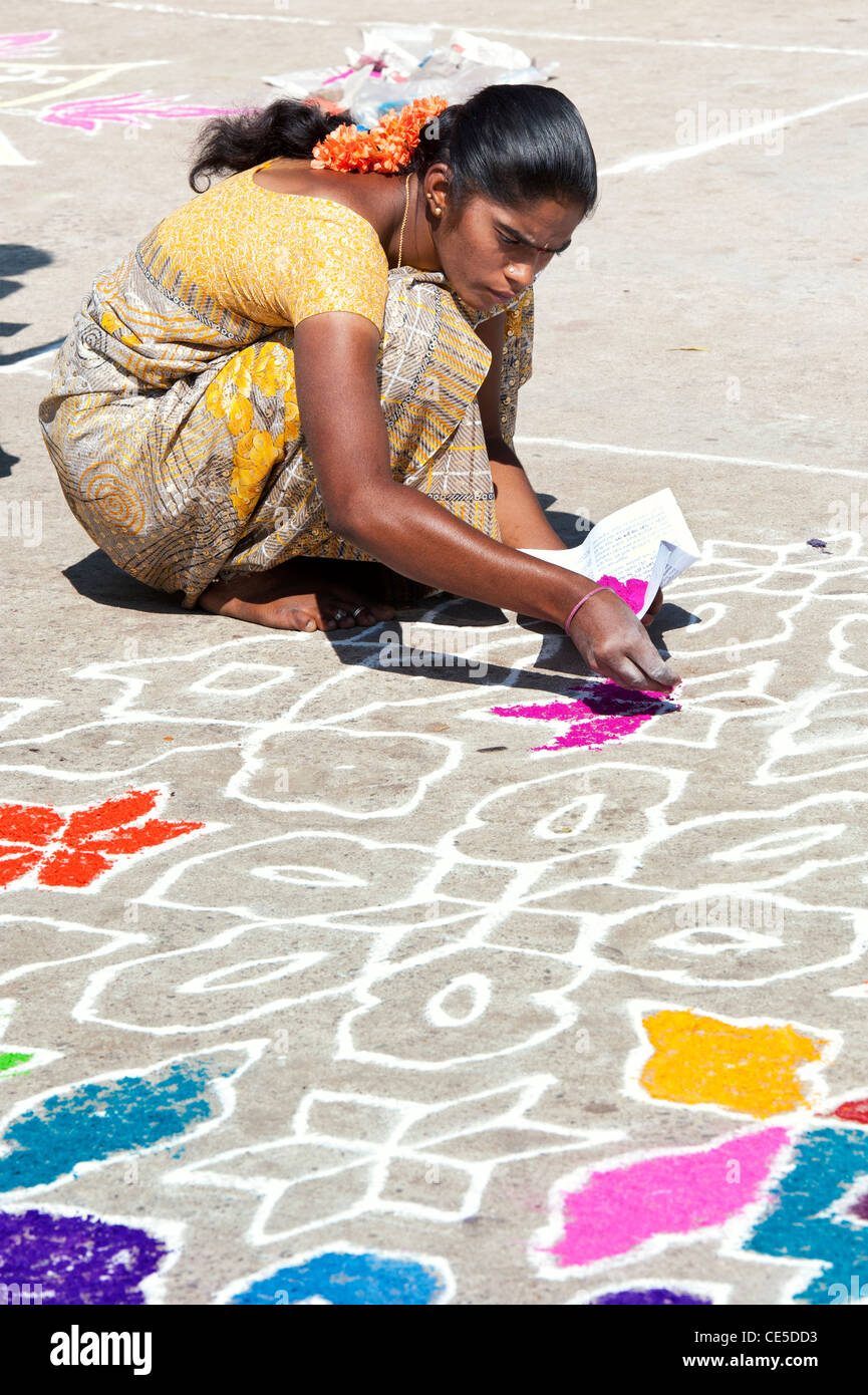 India woman making a Rangoli festival coloured powder design in an Indian street. Puttaparthi, Andhra Pradesh, India Stock Photo