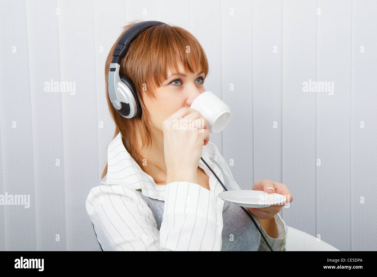 The girl in headphones with a microphone drinks coffee Stock Photo
