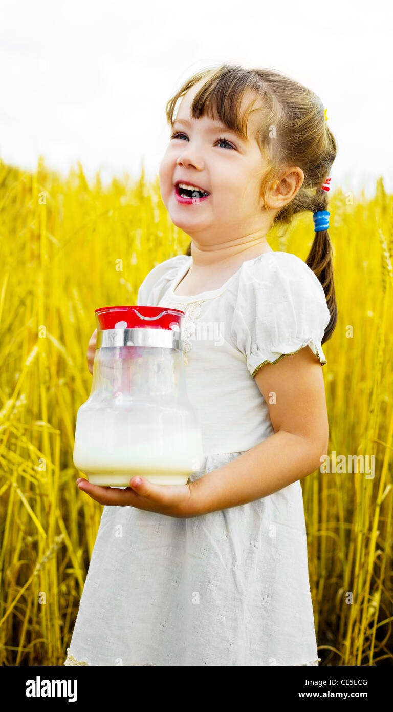 cute happy little girl in the wheat field holding a jug with milk Stock ...