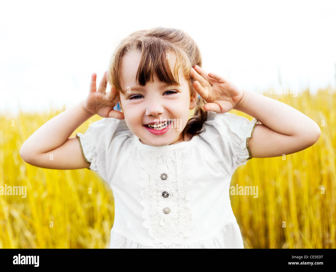 happy cute girl playing and making faces in the wheat field on a warm ...