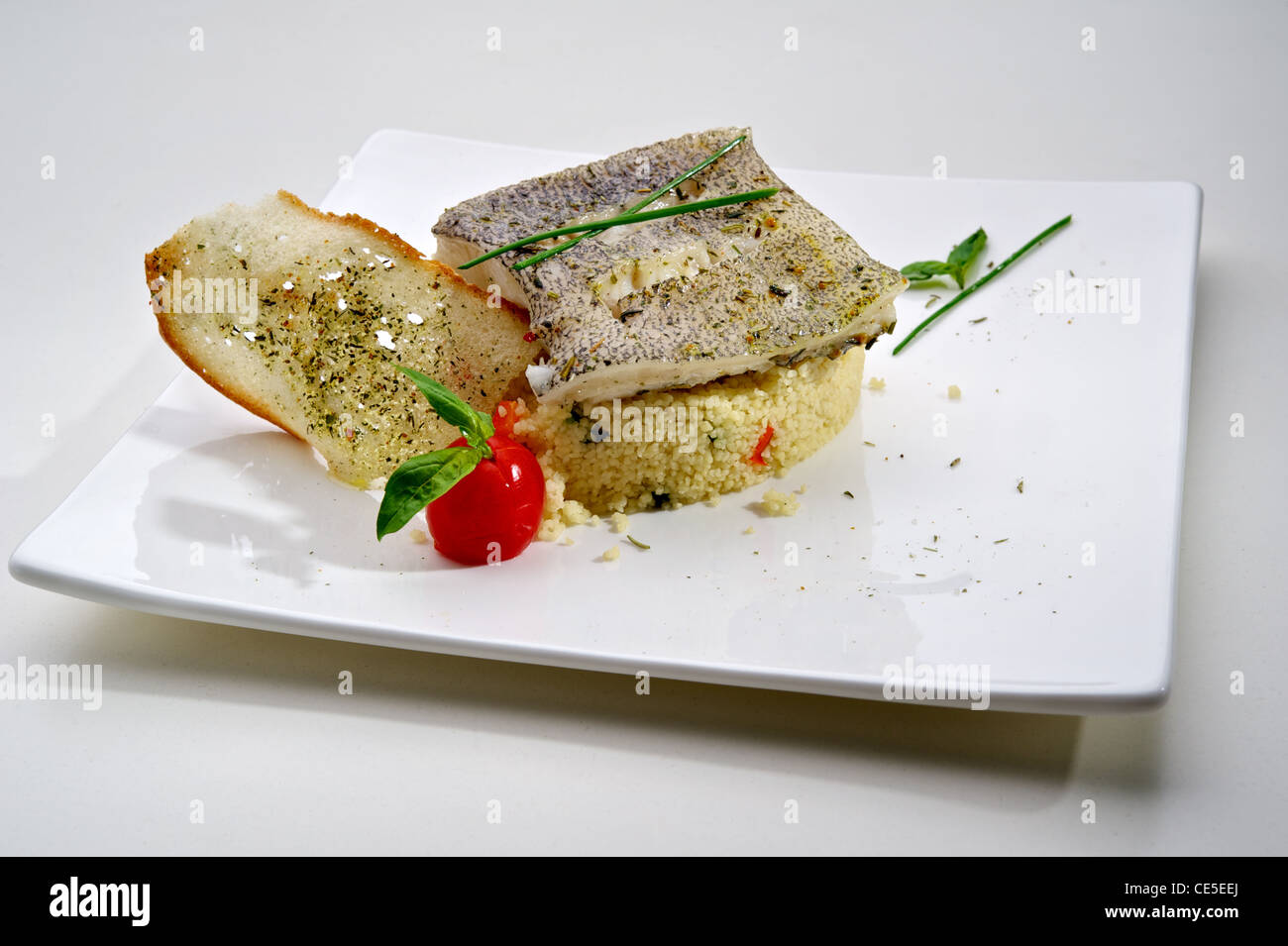 Pike-perch fillet garnished with vegetables and toast, served on white plate Stock Photo