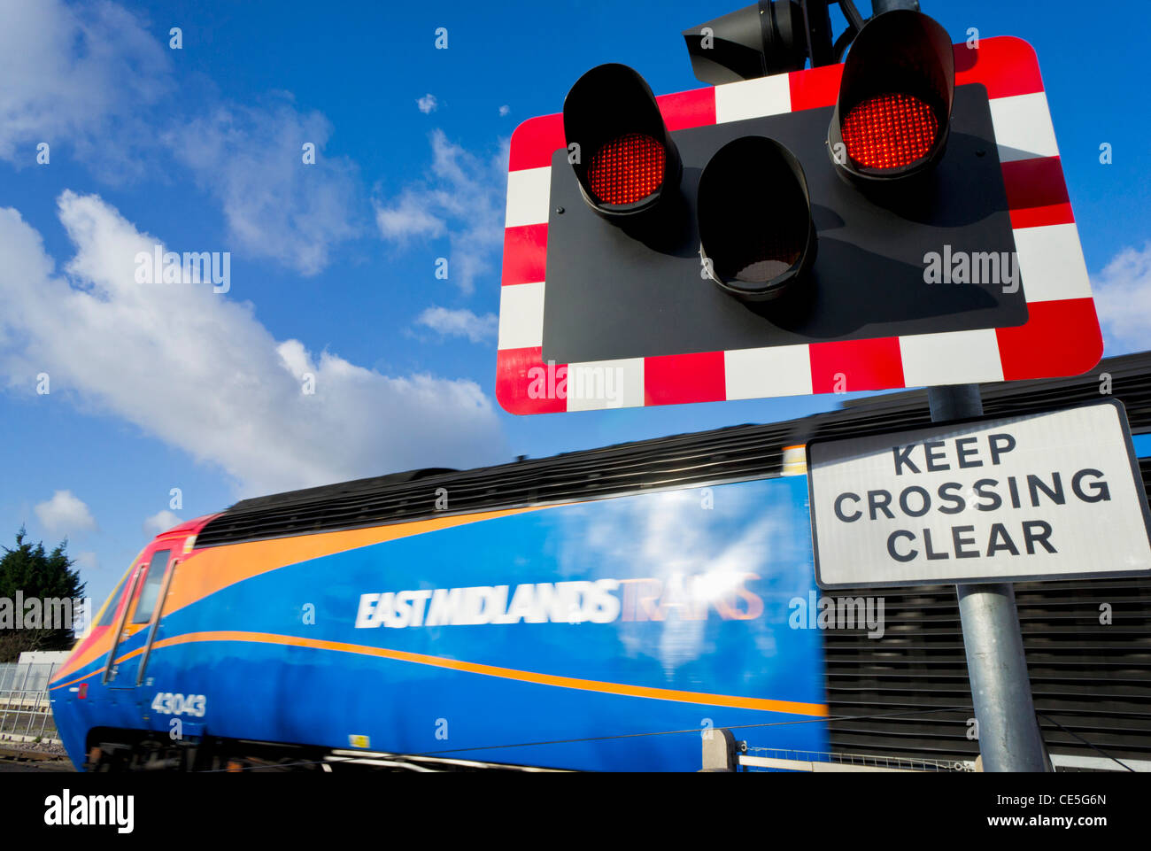 Speeding train passing an automated  railway level crossing sign red light England GB UK Stock Photo