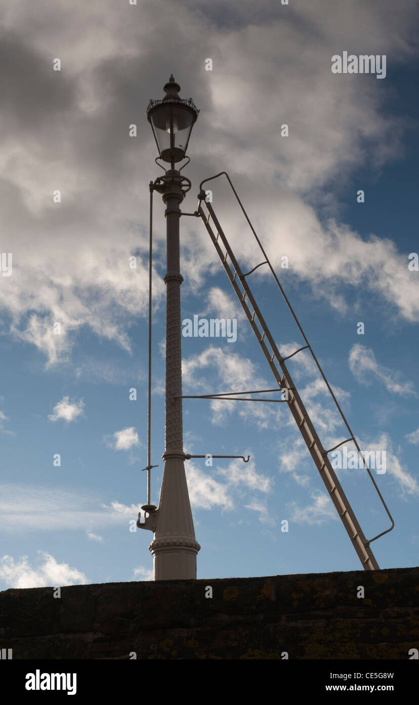 Beacon light on harbour wall against blue and cloudy sky Stock Photo