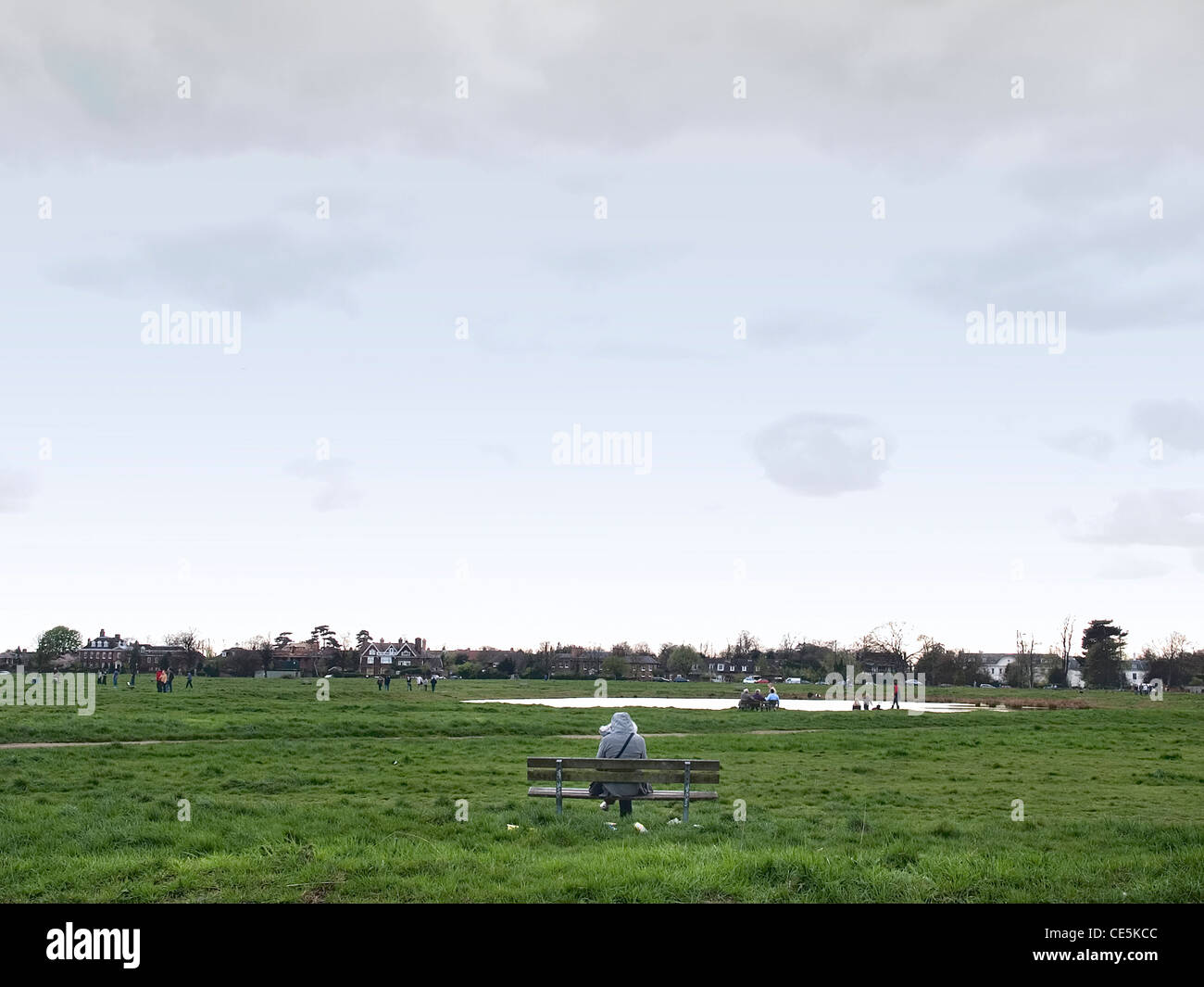 Image of a solitary figure sitting on a park bench Stock Photo