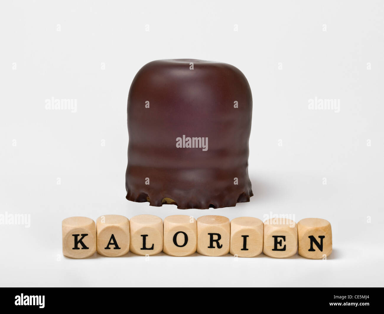 Detail photo of a small chocolate-covered cream cake, alongside are cubes which form the word 'calories' in German Stock Photo