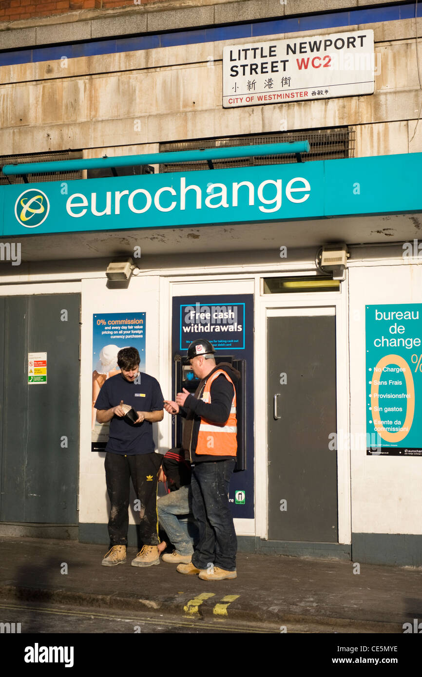 West End Charing Cross Road international London men changing money  Eurochange hole in the wall ATM with road sign in Chinese script street Stock Photo