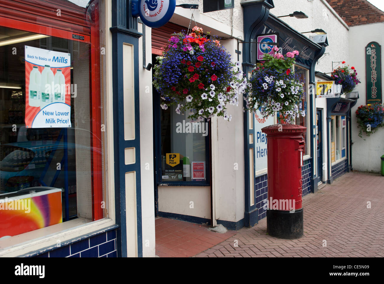 Hanging baskets outside post office shop with pillar box Stock Photo