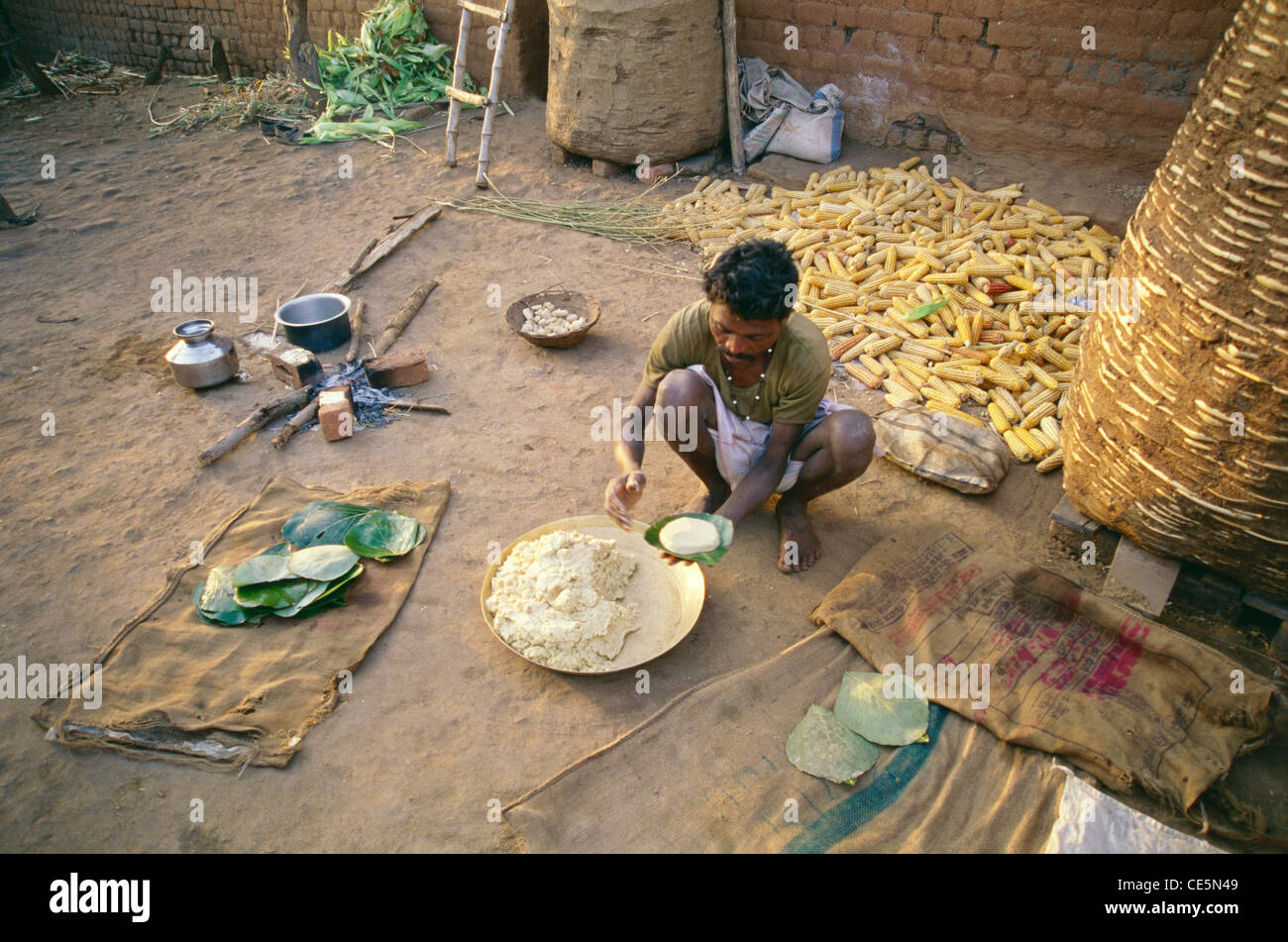 making corn bread bhutta roti on green leaves ; Bhil tribe of Jhabua ; Bihar ; India Stock Photo