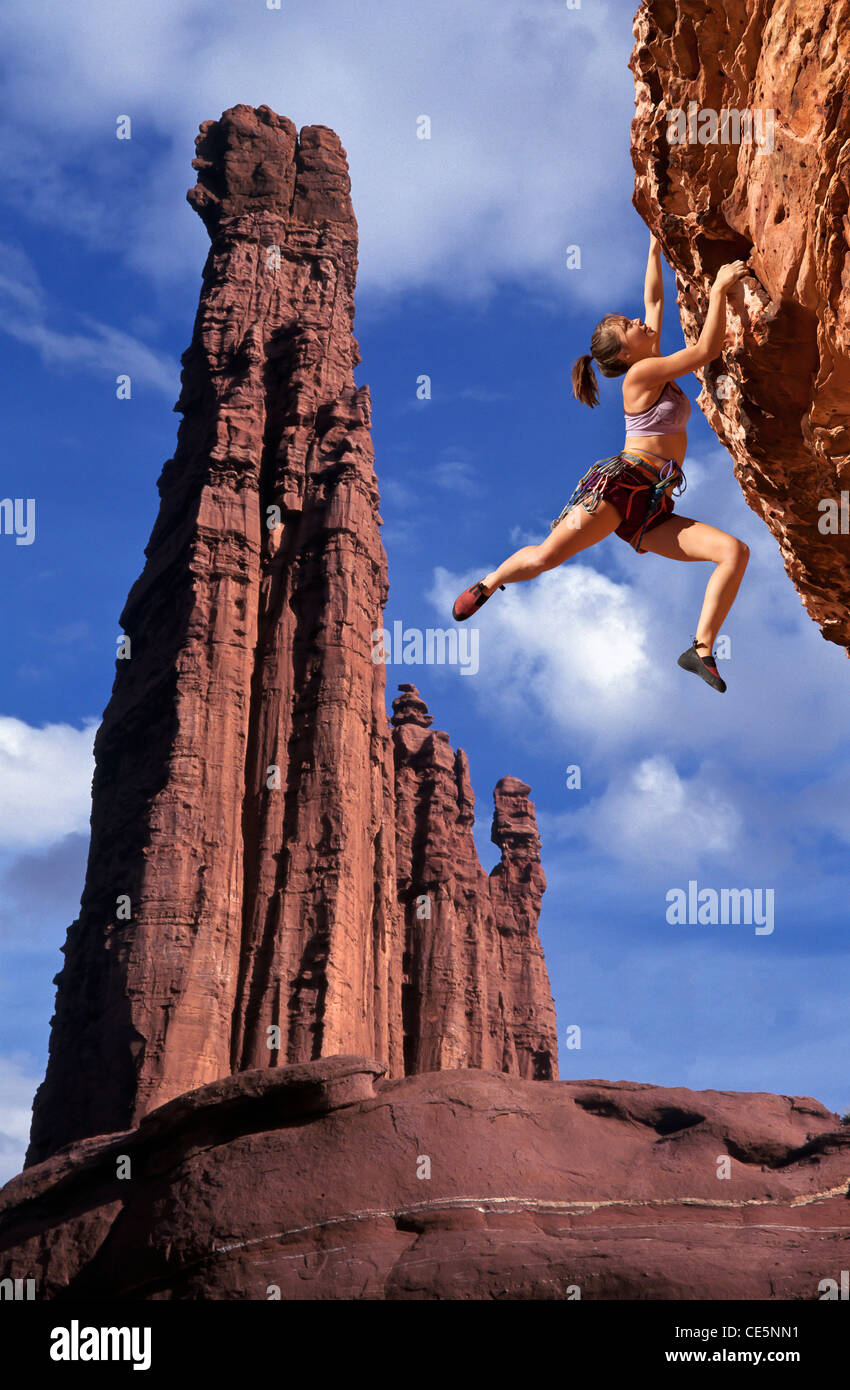 Female rock climber struggles to reach her next grip on the edge of a