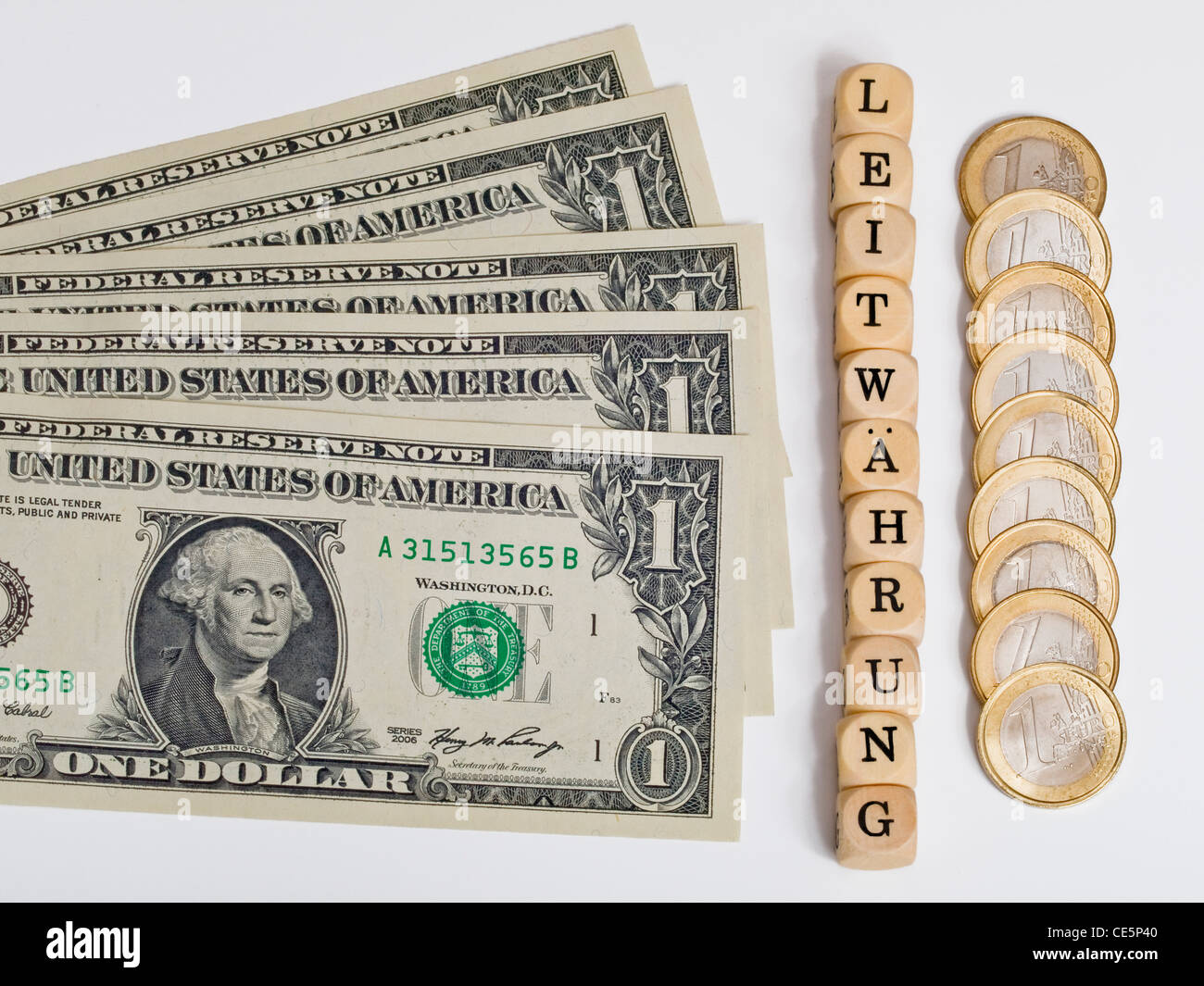 one dollar bills alongside to Euro coins, between this cubes with letters which form the word 'lead currency' in German Stock Photo