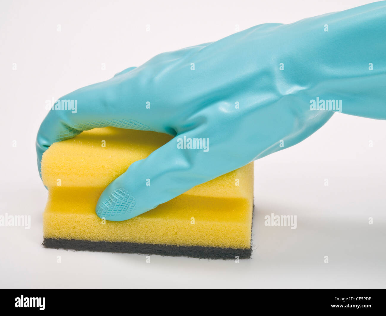 ein Topfschwamm wird mit einem Gummihandschuh festgehalten | a pot sponge is holding tight with a rubber glove Stock Photo