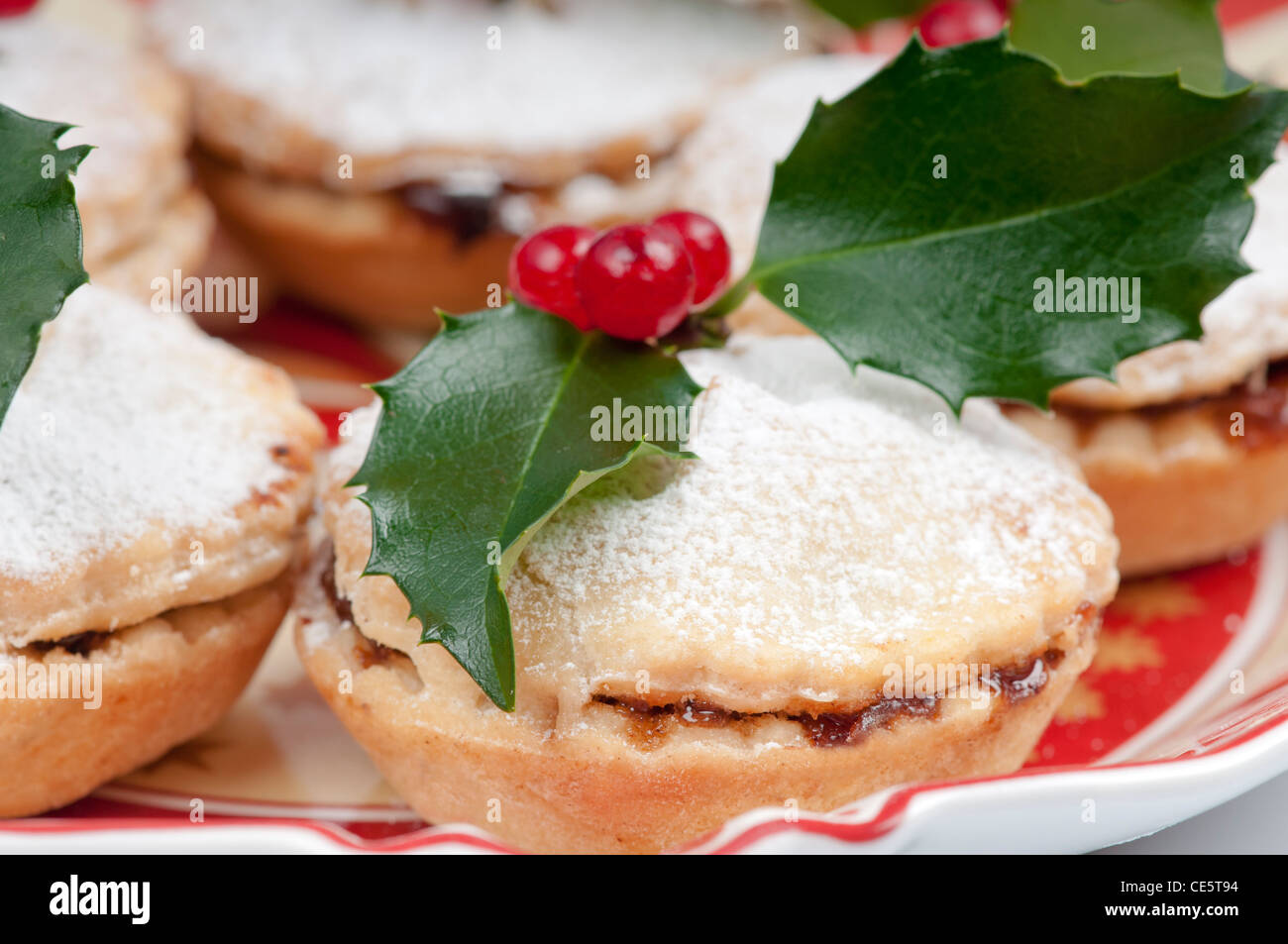 Christmas mincepie decorated with holly and icing sugar on an ...