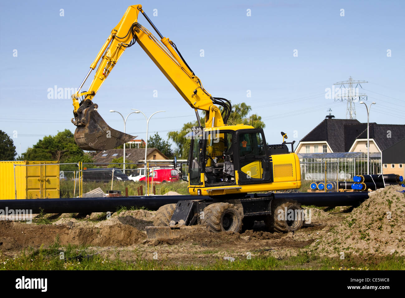 Excavator at work digging up ground for new to build houses - horizontal Stock Photo