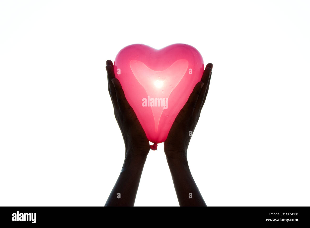 Indian girls hands holding a pink heart shaped balloon Stock Photo