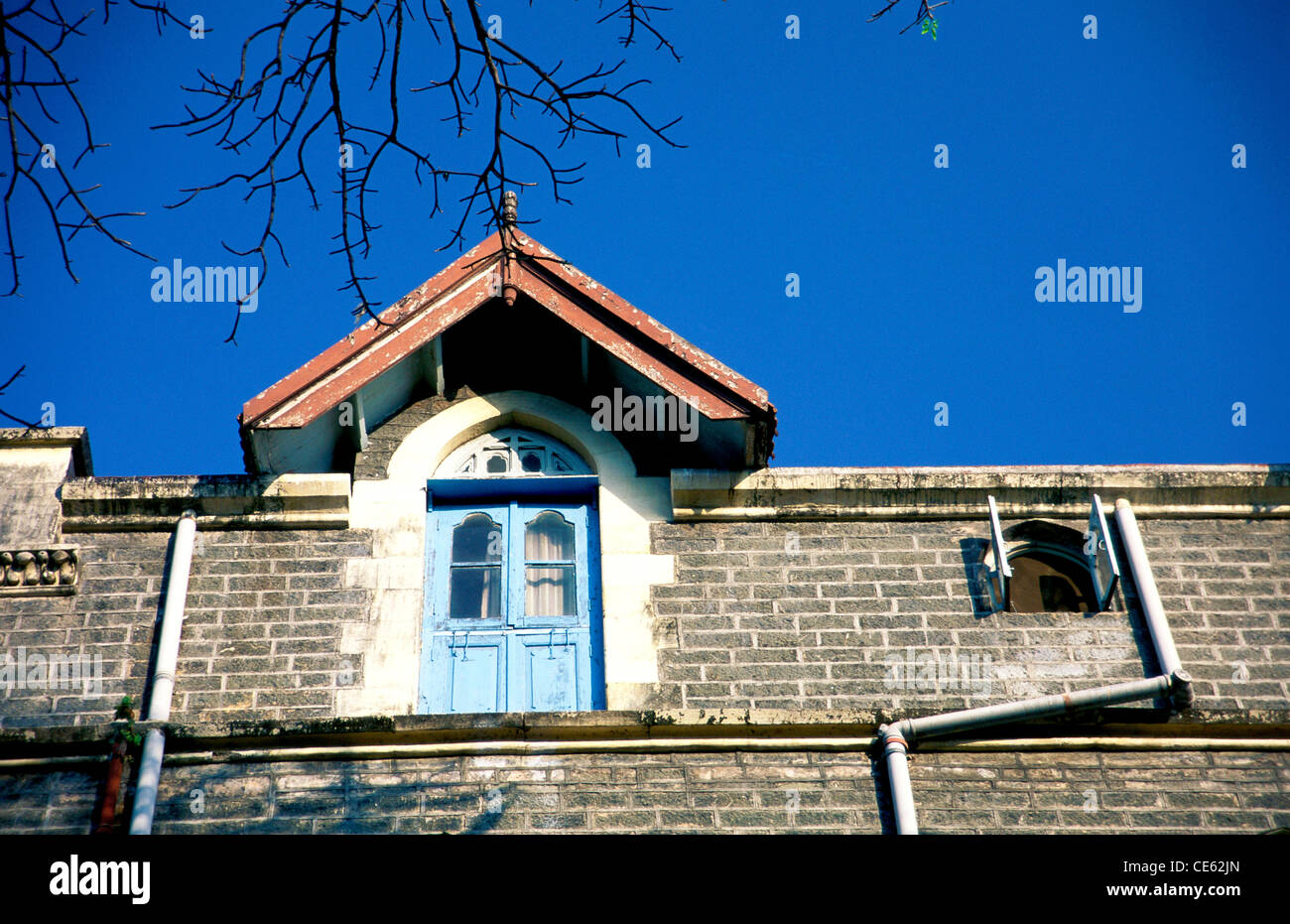 Window triangular roof stone brick wall pipes Xavier's college Bombay Mumbai Maharashtra India Stock Photo